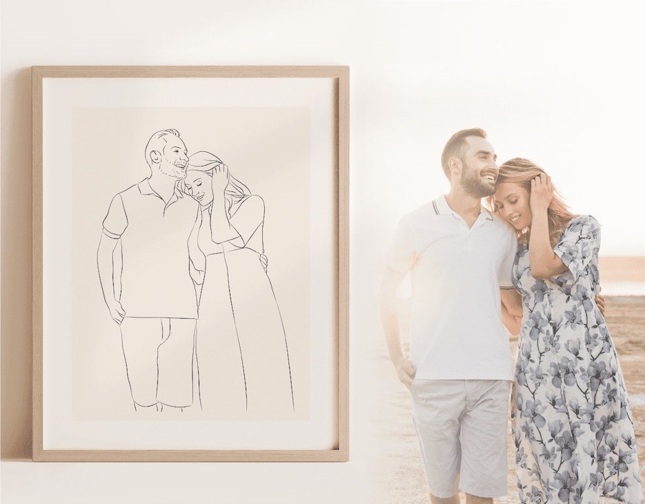 Un'immagine Miroar Line Art in una cornice in legno di quercia accanto a una giovane coppia sulla spiaggia