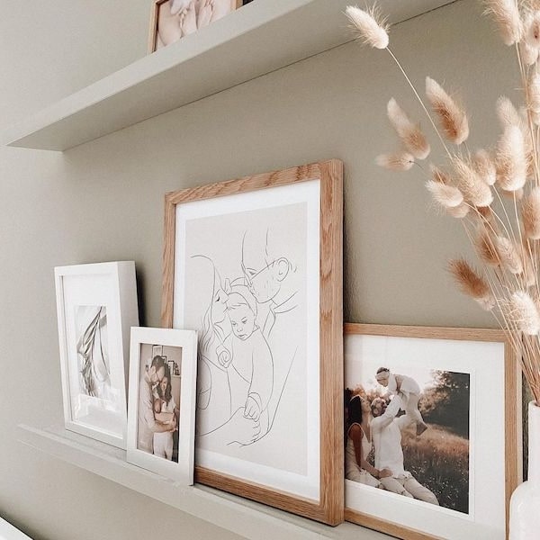 Parete con foto di famiglia, tra cui un disegno Line Art di una giovane famiglia, post Instagram di @adriane